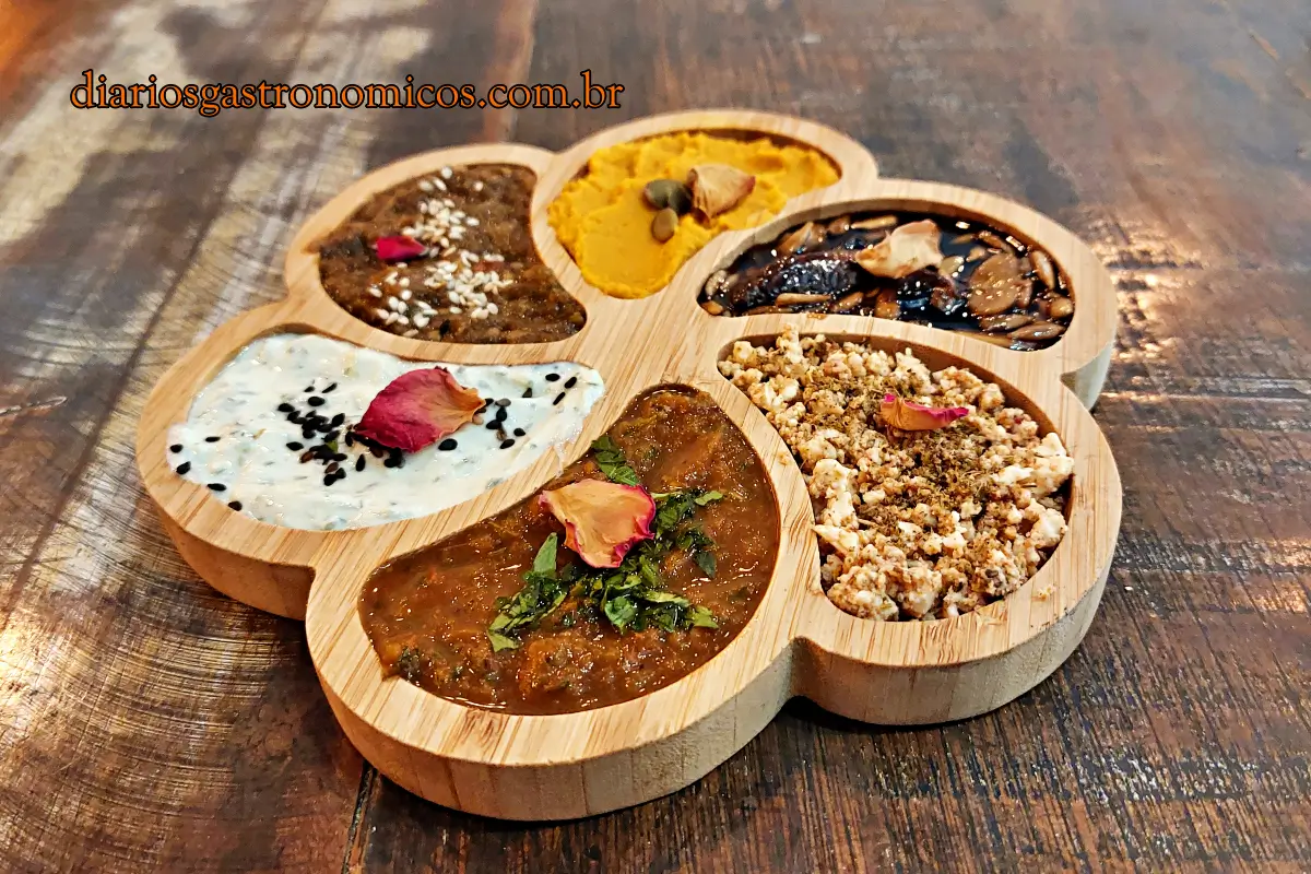mix de mezes, tipicas pastas servidas como entrada na culinária turca Six-section wooden serving platter with diverse dishes: curry, yogurt with sesame, turmeric, and crumble on a rustic table.