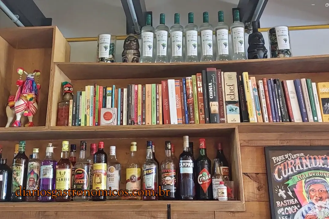 Decoração interna do restaurante peruano Doña Bertha em São Paulo, com livros, garrafas de pisco e objetos culturais peruanos.