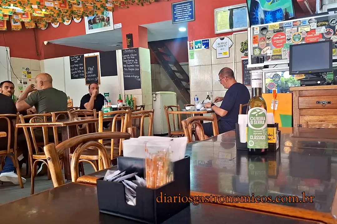 Interior do Bar Sambódromo, na Cidade Nova, com mesas, cadeiras de madeira e decoração típica de um boteco carioca.