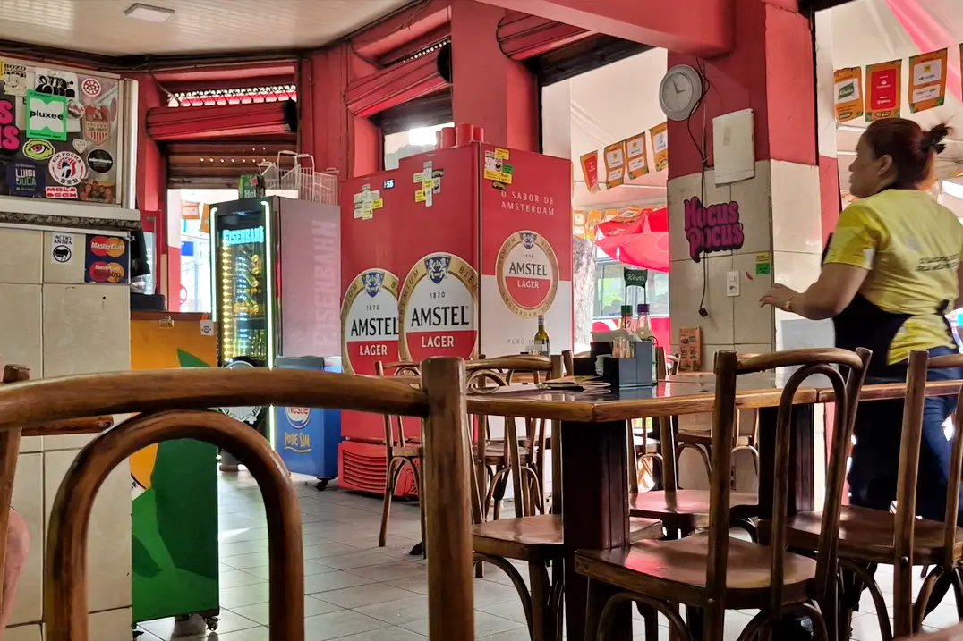 Vista interna do Bar Sambódromo, tradicional botequim da Praça XI, no Rio de Janeiro, com mesas de madeira e ambiente descontraído.