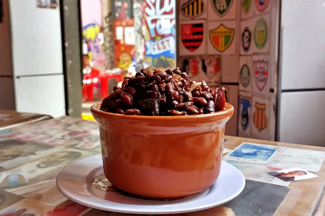 Feijoada do Bar do Adalto servida na panela de barro com carnes variadas e feijão preto.