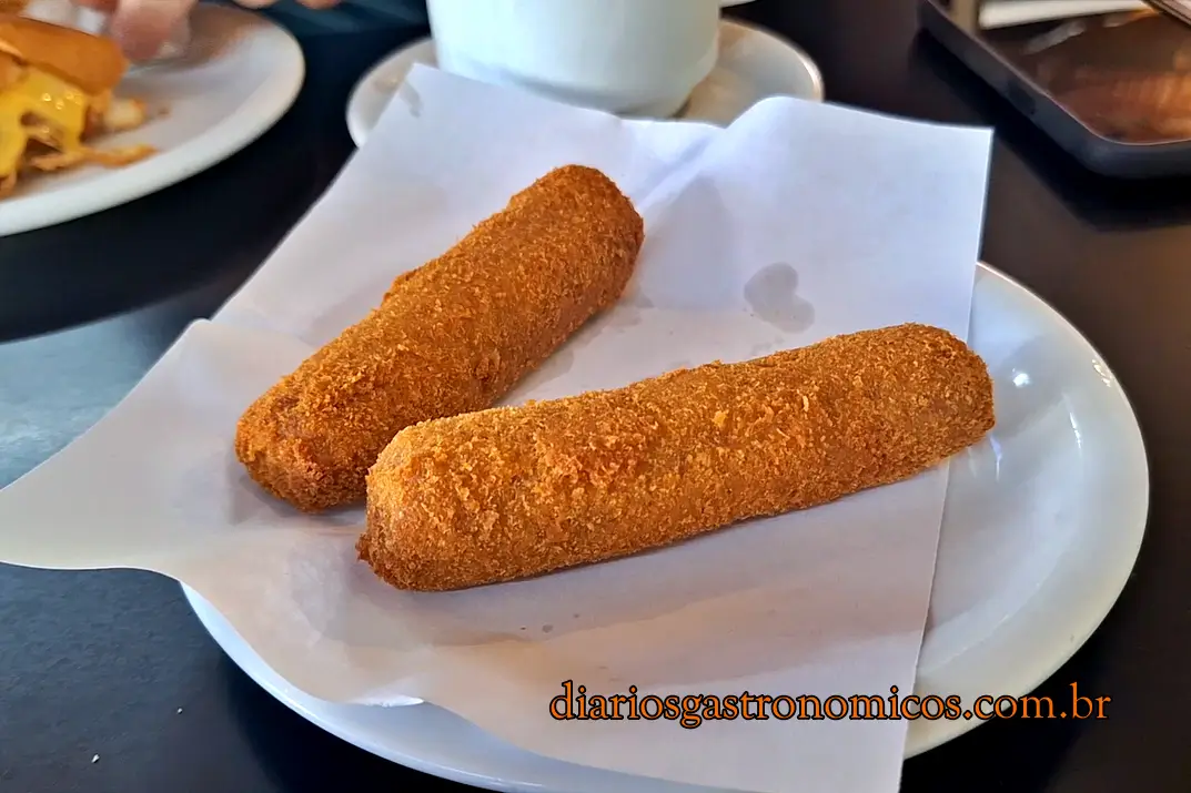 Dois croquetes tradicionais da Casa do Alemão servidos em um prato branco sobre a mesa, especialidade clássica da gastronomia de Petrópolis.