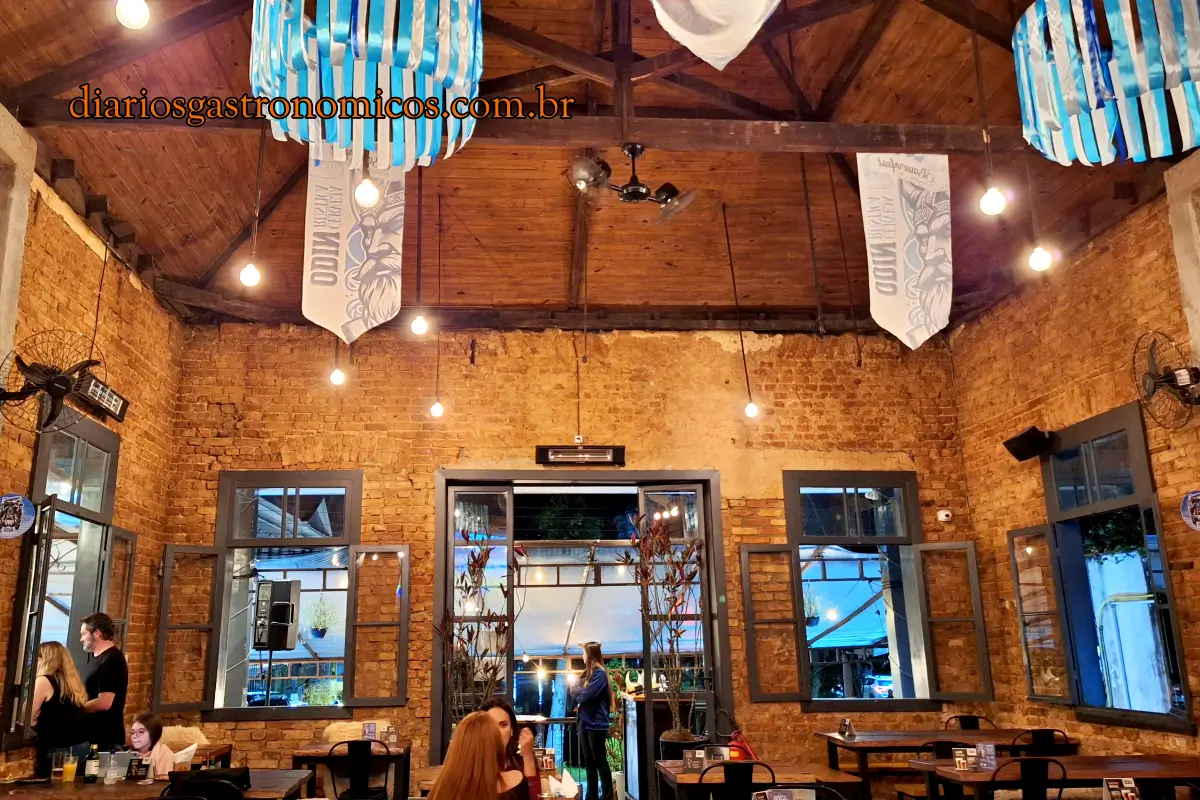 Salão interno da Cervejaria Odin em Petrópolis, com paredes de tijolos aparentes, pé-direito alto, decoração viking e mesas para os clientes.