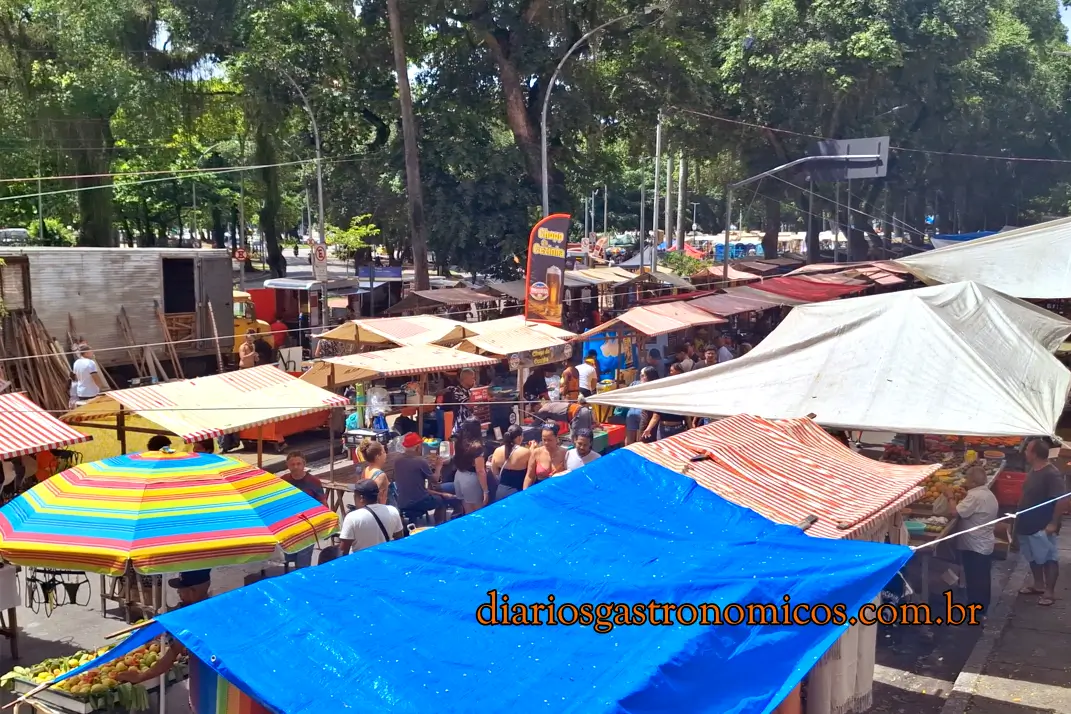 Vista da Feira da Glória no Rio de Janeiro com barracas de comida, artesanato e grande movimento de visitantes.