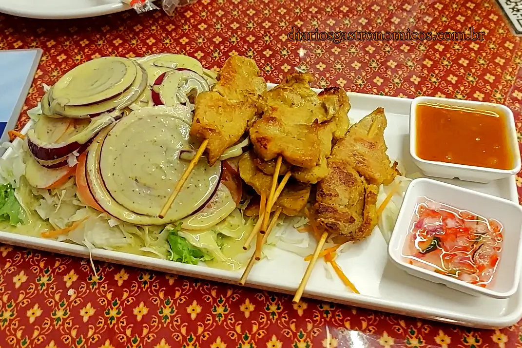 Satek do Thai E-San, entrada típica da culinária tailandesa com espetinhos de carne de porco marinados, salada e molho Satay preparado com amendoim, curry e leite de coco.