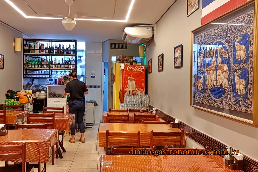 Interior do restaurante Thai E-San, na Liberdade, em São Paulo, com decoração inspirada na Tailândia, ambiente simples, mesas de madeira e referências à cultura tailandesa.