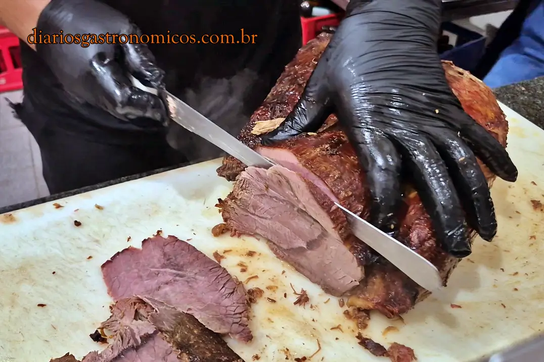 Funcionário do Opus cortando uma peça de carne assada utilizada nos tradicionais sanduíches da casa.