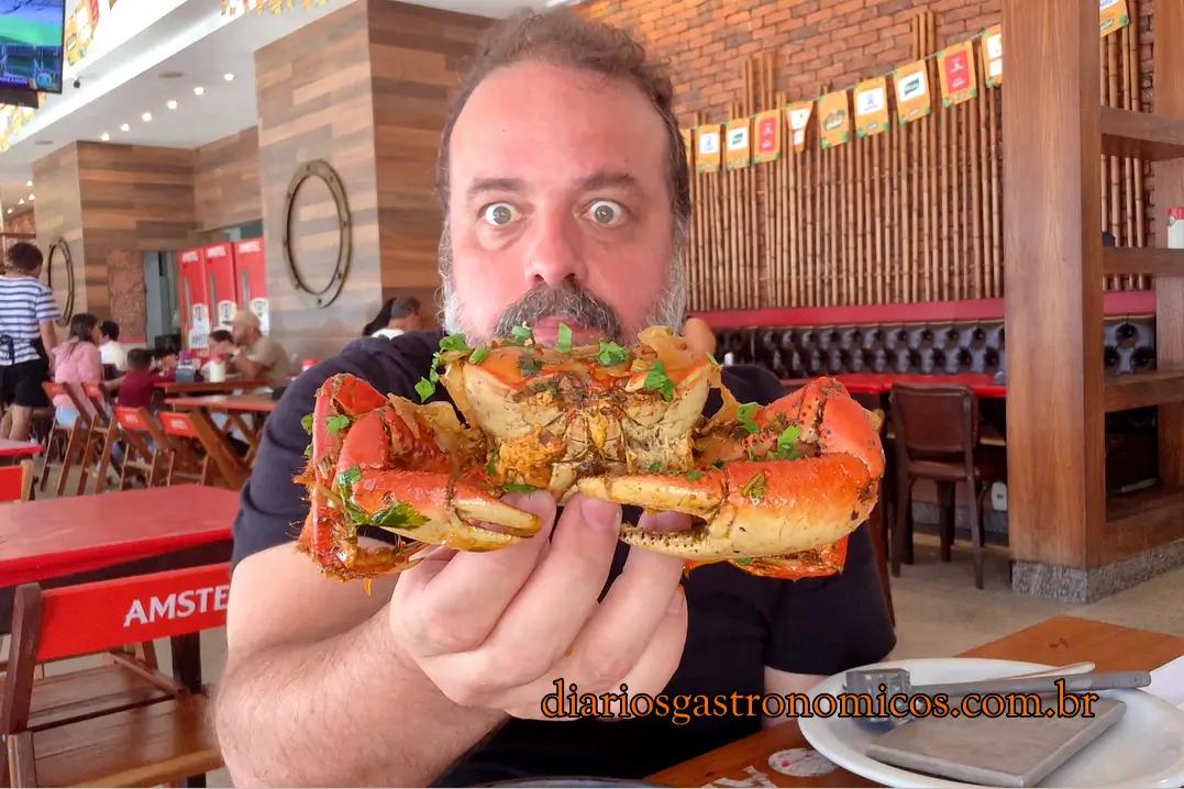 André Comber segura um grande caranguejo servido no Edinho do Caranguejo durante gravação do Diários Gastronômicos.