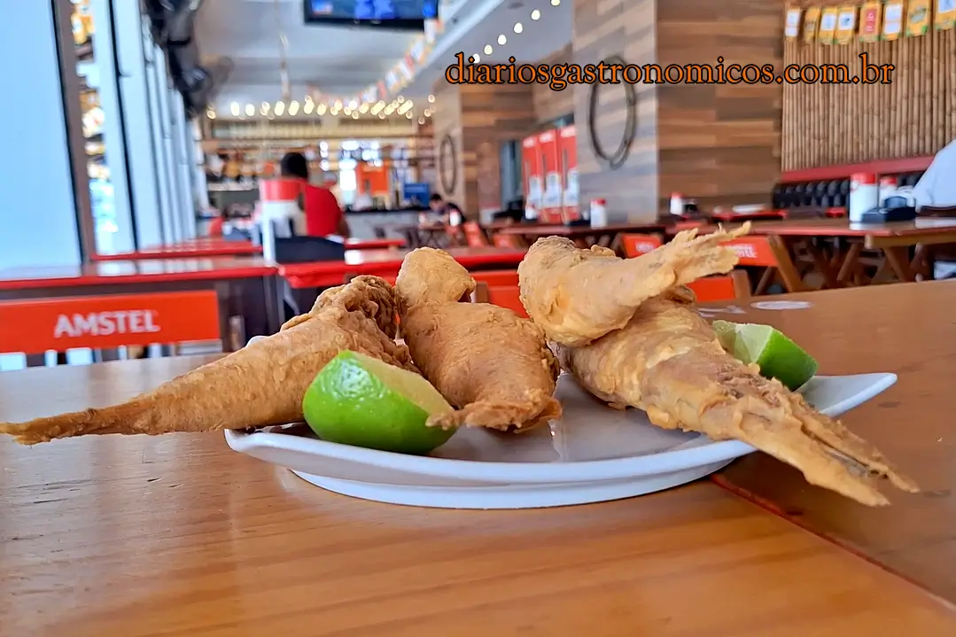 Porção de trilha frita servida com limão no Edinho do Caranguejo, famosa pela fritura crocante.