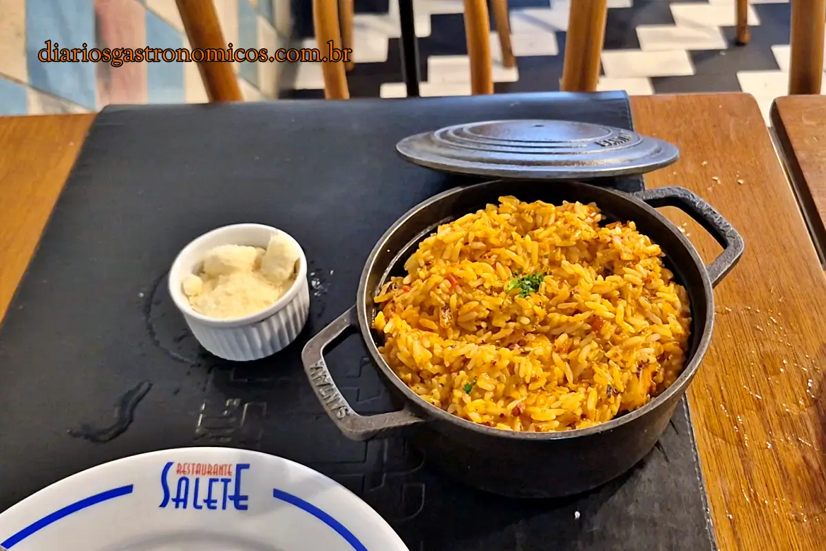 Panela de ferro com risoto de polvo servido no Restaurante Salete acompanhada de queijo ralado.
