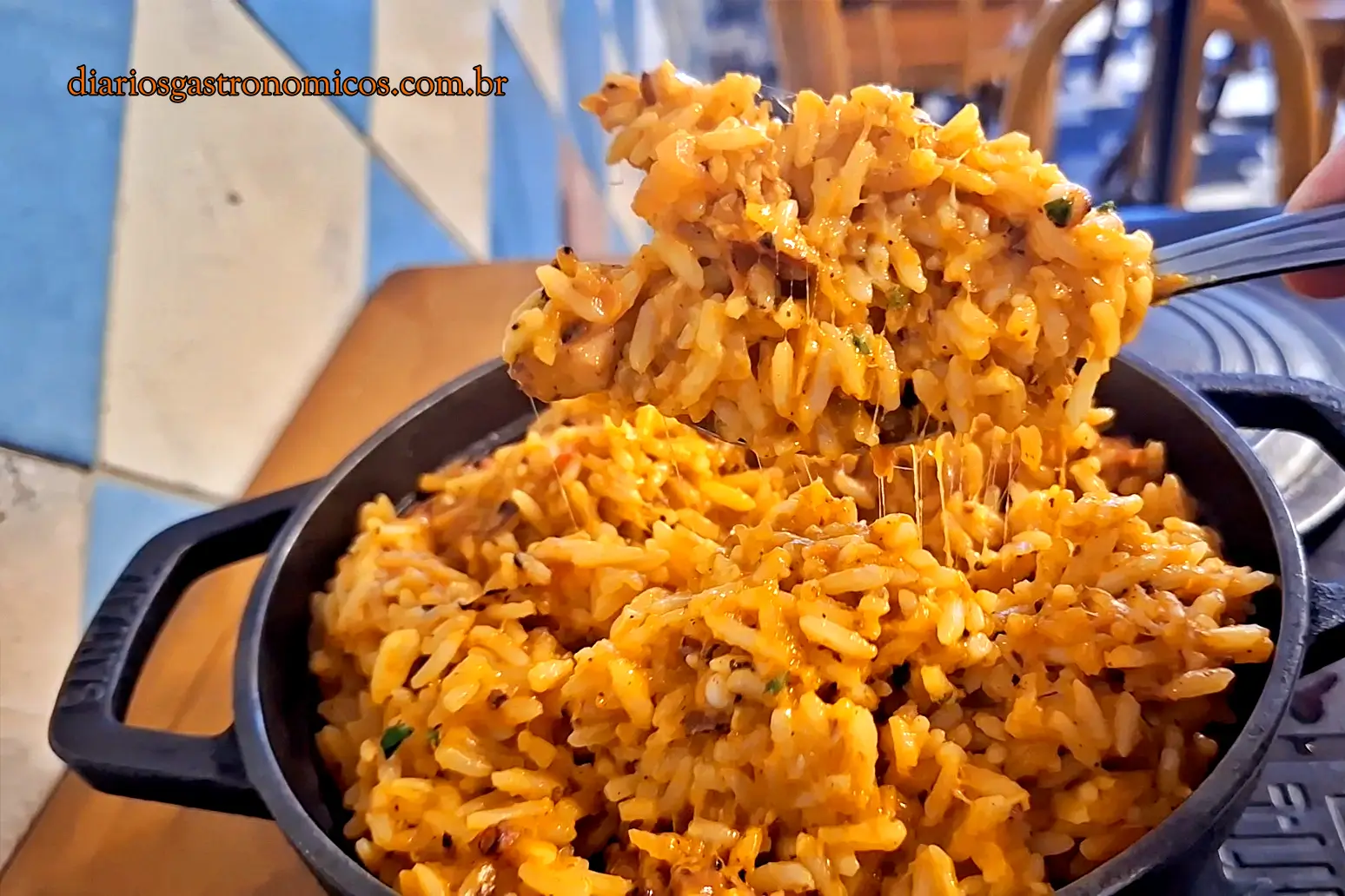 Close de colher retirando porção de risoto de polvo cremoso servido em panela de ferro no Restaurante Salete.