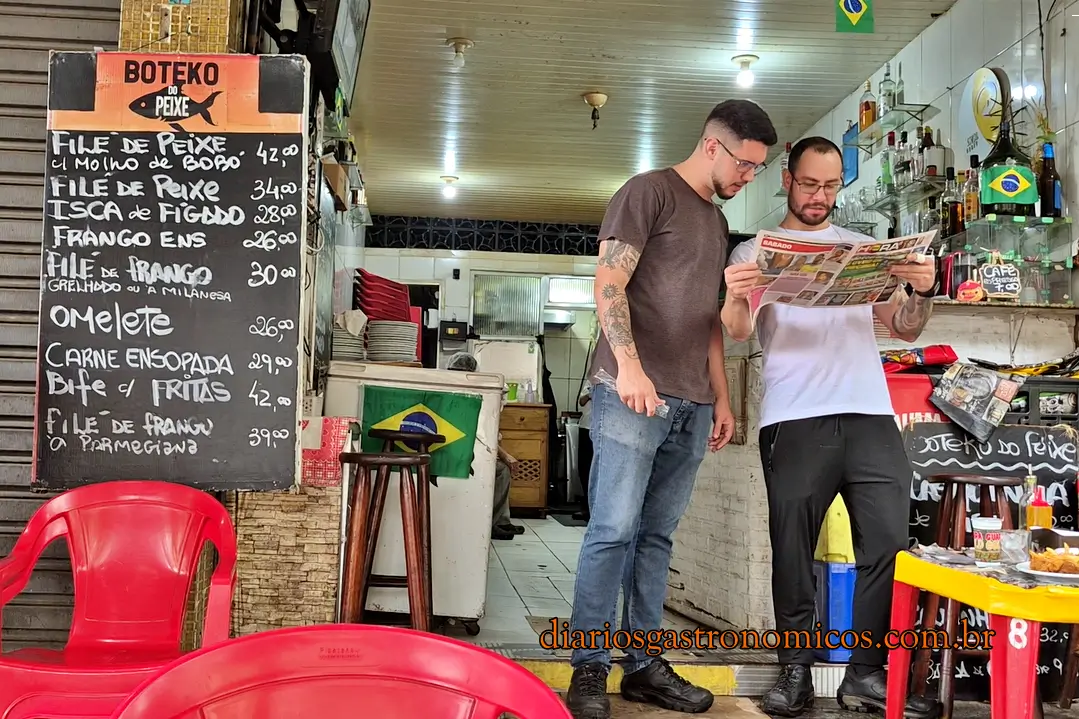 Fachada e área de atendimento do Boteko do Peixe, com mesas e cadeiras de plástico vermelhas e quadro com pratos e preços, na Praça da Bandeira, Rio de Janeiro